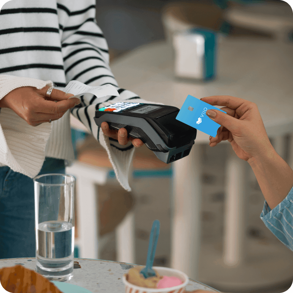 Persona acerca la tarjeta azul VIIO a un datáfono para realizar el pago de una compra en una cafetería.